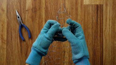 Forming a cone with chicken wire with gloved hands.