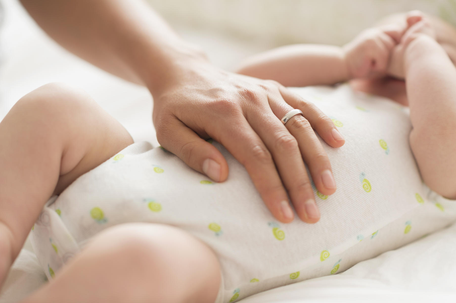 Mother massaging belly of baby boy